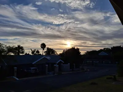 a cloudy sky with the sun setting behind houses at Spacious Suite Somerset West in Somerset West