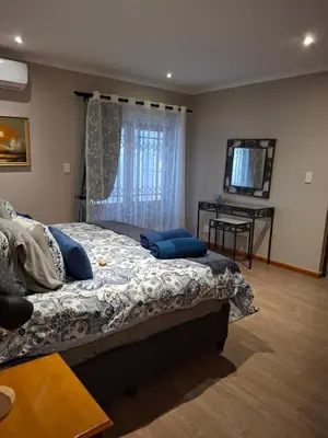 a bedroom with a bed with blue pillows on it at Spacious Suite Somerset West in Somerset West