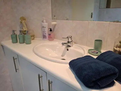 a bathroom sink with two towels and a mirror at Spacious Suite Somerset West in Somerset West