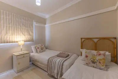 a small bedroom with two beds and a lamp at Fleurpark 6 in Gordonʼs Bay