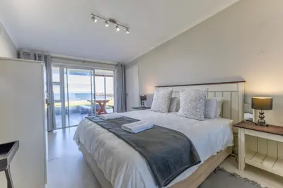 a bedroom with a large bed with a view of the ocean at Fleurpark 6 in Gordonʼs Bay