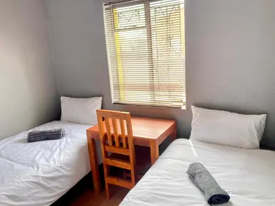 a room with two beds and a table and a chair at Unit 1, TraversHub Sleeps 6 Self-Catering Group Belhar, CT in Belhar