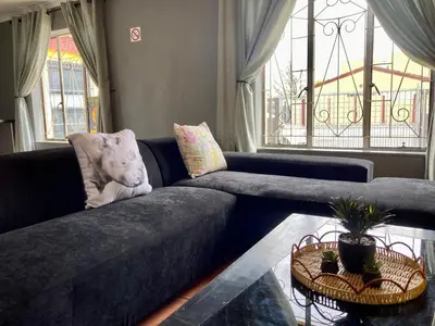 a living room with a blue couch with a teddy bear on it at Unit 1, TraversHub Sleeps 6 Self-Catering Group Belhar, CT in Belhar