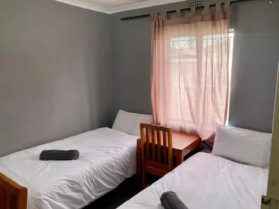 a bedroom with two twin beds and a window at Unit 1, TraversHub Sleeps 6 Self-Catering Group Belhar, CT in Belhar