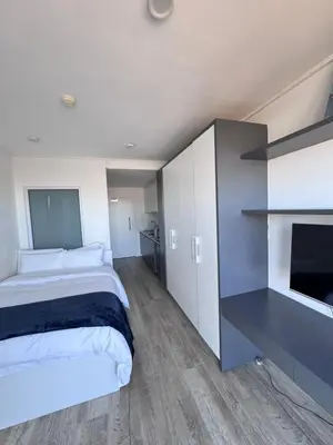 a bedroom with a bed and a desk and a tv at Harbour View Modern Studio at One on Albert in Cape Town