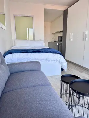 a bedroom with a bed and a couch and a kitchen at Harbour View Modern Studio at One on Albert in Cape Town