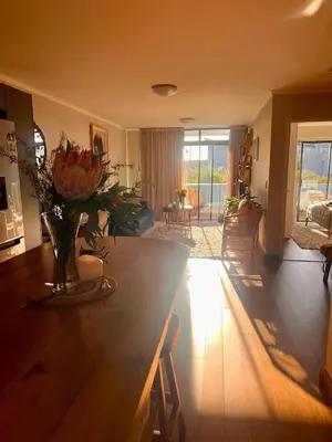 a living room with a table with a vase of flowers at Divine Apartment Century City in Cape Town
