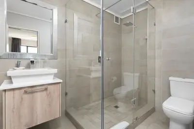 a bathroom with a shower and a toilet and a sink at LuxeStay 2-Bed Century City Gem in Cape Town