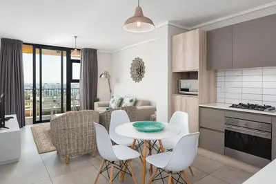 a kitchen and living room with a table and chairs at LuxeStay 2-Bed Century City Gem in Cape Town