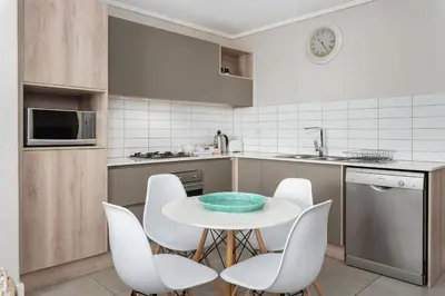 a kitchen with a white table and white chairs at LuxeStay 2-Bed Century City Gem in Cape Town