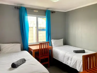 a room with two beds and a table and a window at Unit 2 TraversHub Sleeps 6 Self-Catering Group Belhar, CT in Belhar