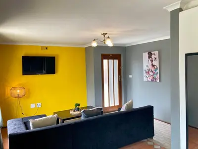 a living room with a couch and a yellow wall at Unit 2 TraversHub Sleeps 6 Self-Catering Group Belhar, CT in Belhar