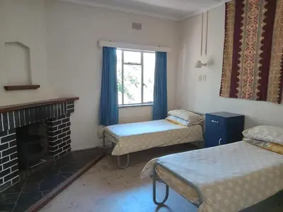 a room with two beds and a fireplace and a window at A Rustic and Reflective Nature Getaway in Greyton in Greyton
