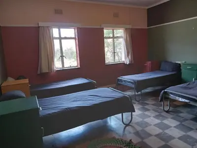 a room with two beds and a couch and windows at A Rustic and Reflective Nature Getaway in Greyton in Greyton