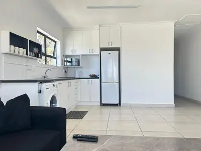 a kitchen with white cabinets and a refrigerator at Shine house in Somerset West