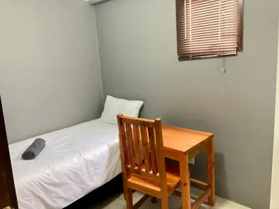 a small bedroom with a bed and a wooden table at Unit 3 TraversHub Sleeps 6 Self-Catering Group Belhar, CT in Belhar