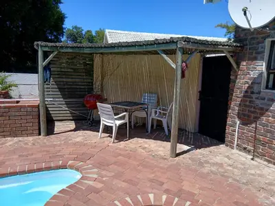 a patio with a table and chairs next to a pool at Chasselas Studio in Somerset West