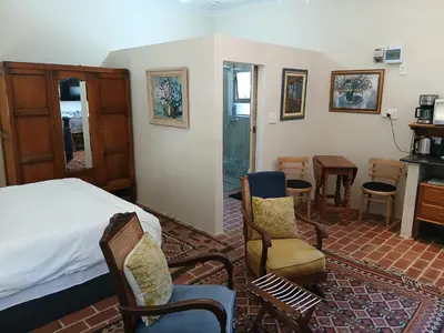 a bedroom with a bed and a table and chairs at Chasselas Studio in Somerset West