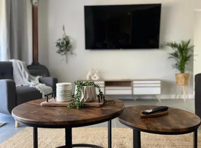 a living room with two tables and a tv at Rissie's 3 Bedroom Apartment in Gordonʼs Bay