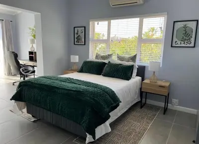 a bedroom with a bed and a desk and a window at Rissie's 3 Bedroom Apartment in Gordonʼs Bay