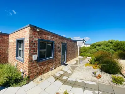 a brick house with two windows and a patio at Fynbossie in Pringle Bay