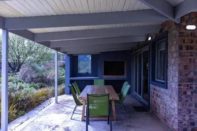 a patio with a table and chairs on it at Fynbossie in Pringle Bay