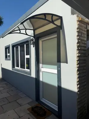 a garage door with awning on the side of a house at Sunny Snooze Holiday Home in Goodwood