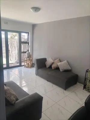 a living room with a couch sitting on a tile floor at Beach Vibes Villa in Cape Town