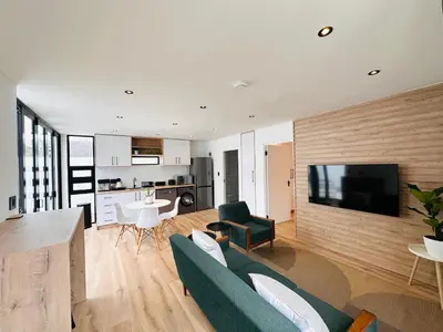 a living room with a couch and a tv at Modern Scandinavian Luxury Apartment in Hermanus