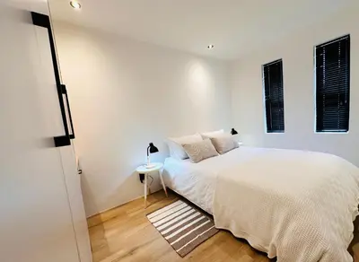 a white bedroom with a bed and a window at Modern Scandinavian Luxury Apartment in Hermanus