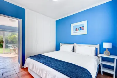 a blue bedroom with a bed with a blue wall at Sea Breeze Kite Dreams 3 in Cape Town