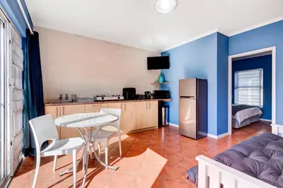 a kitchen and living room with a table and a refrigerator at Sea Breeze Kite Dreams 3 in Cape Town