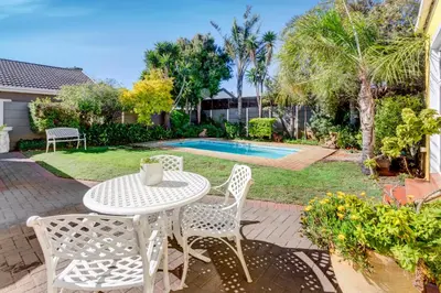 a patio with a table and chairs and a pool at Sea Breeze Kite Dreams 3 in Cape Town