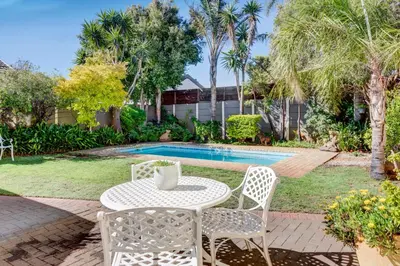 a table and chairs next to a swimming pool at Sea Breeze Kite Dreams 3 in Cape Town