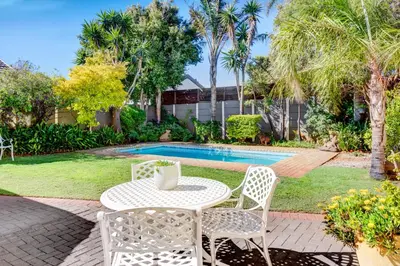 a patio with a table and chairs next to a pool at Sea Breeze Kite Dreams 3 in Cape Town