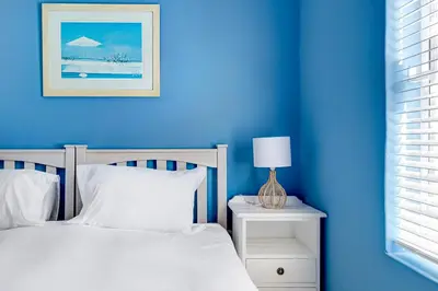 a blue bedroom with a bed and a lamp on a night stand at Sea Breeze Kite Dreams 3 in Cape Town