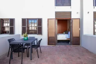 a patio with a table and chairs and a bed at 9 at Huis Piron - Location Stellies Central in Stellenbosch