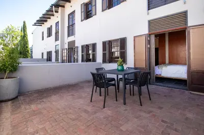 a patio with a table and chairs and a bedroom at 9 at Huis Piron - Location Stellies Central in Stellenbosch