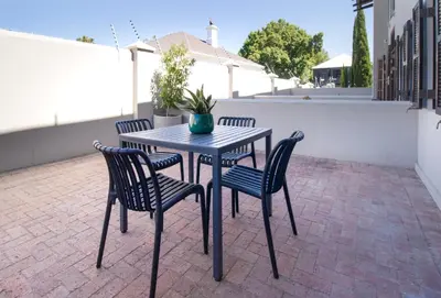 a table and chairs on a patio with a potted plant at 9 at Huis Piron - Location Stellies Central in Stellenbosch