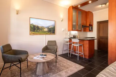 a living room with a table and chairs and a kitchen at 9 at Huis Piron - Location Stellies Central in Stellenbosch