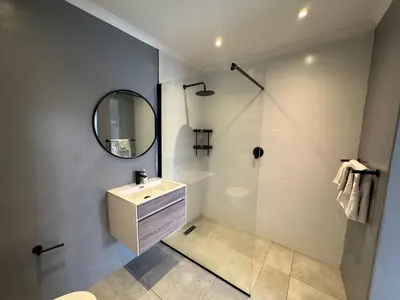 a bathroom with a sink and a shower with a mirror at One-Bedroom apartment in Somerset West in Helderberg