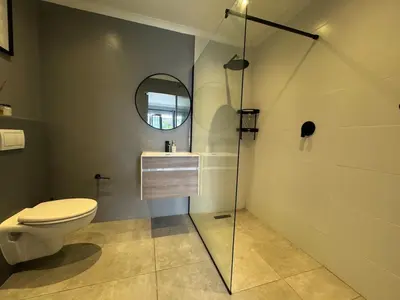 a bathroom with a toilet and a sink and a mirror at One-Bedroom apartment in Somerset West in Helderberg