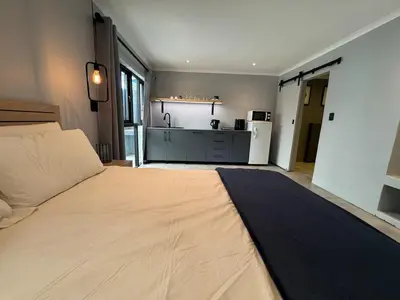 a bedroom with a large bed and a kitchen at One-Bedroom apartment in Somerset West in Helderberg