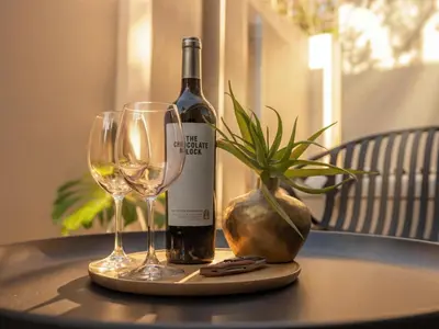 a bottle of wine and two glasses on a table at Guesthouse Ubuntu - Stellenbosch in Stellenbosch