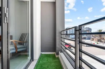 a balcony with green grass and a chair at Beach Break 17 in Cape Town