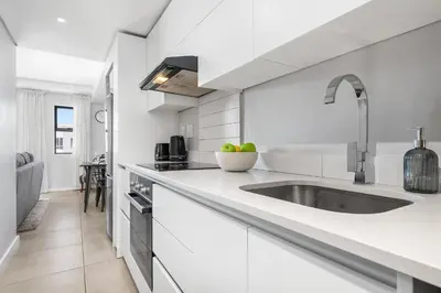 a white kitchen with a sink and a counter at Beach Break 17 in Cape Town