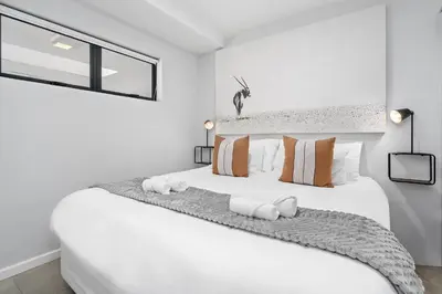 a white bedroom with a large white bed with pillows at Beach Break 17 in Cape Town