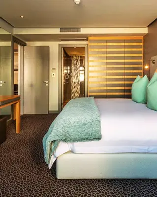 a bedroom with a bed and a desk in a room at Krystal Beach Hotel in Gordonʼs Bay