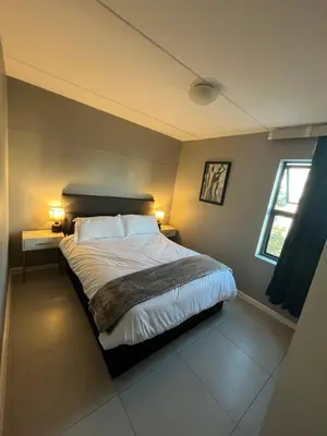 a bedroom with a bed with two lamps and a window at Minimalist 2 bed 1 full bathroom in Cape Town