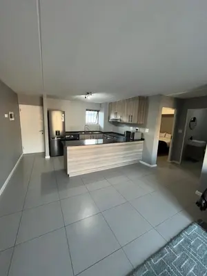 an empty living room with a kitchen and a large room at Minimalist 2 bed 1 full bathroom in Cape Town